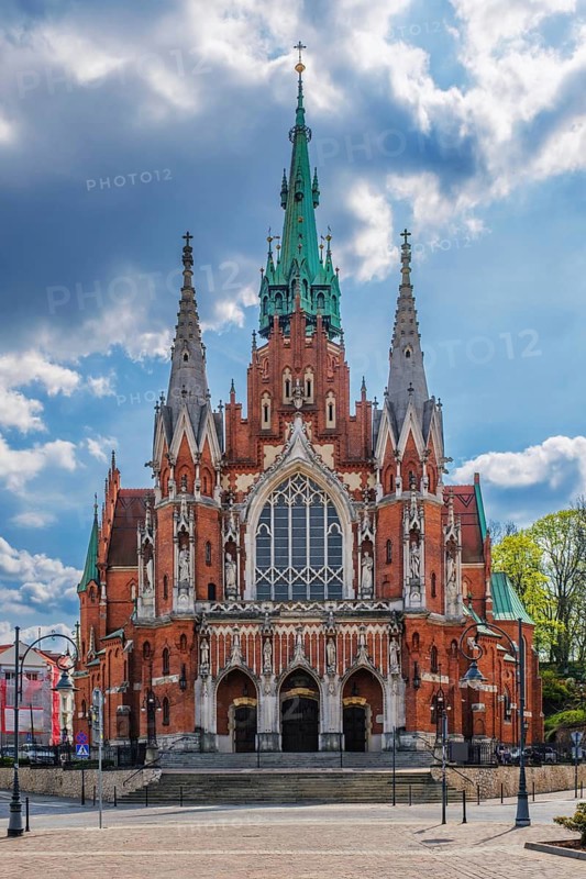 Close view of Saint Joseph Church in Podgorze, Krakow, Poland, showing red brick Gothic architecture, tall steeples, church facade, blue sky, and no people