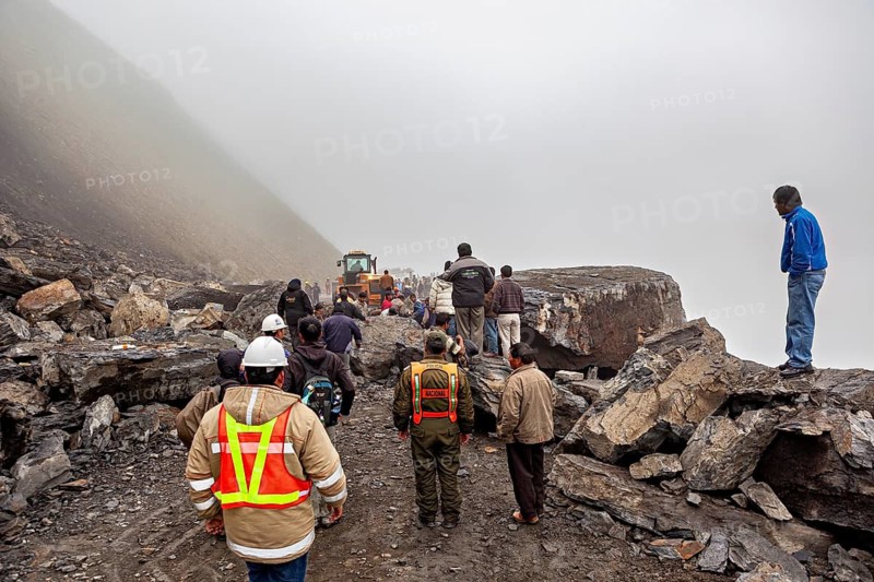 People work on a large, rocky construction site in fog, rockslide on the pass road towards Rurrenabaque through the Andes on the Road of Death in Bolivia