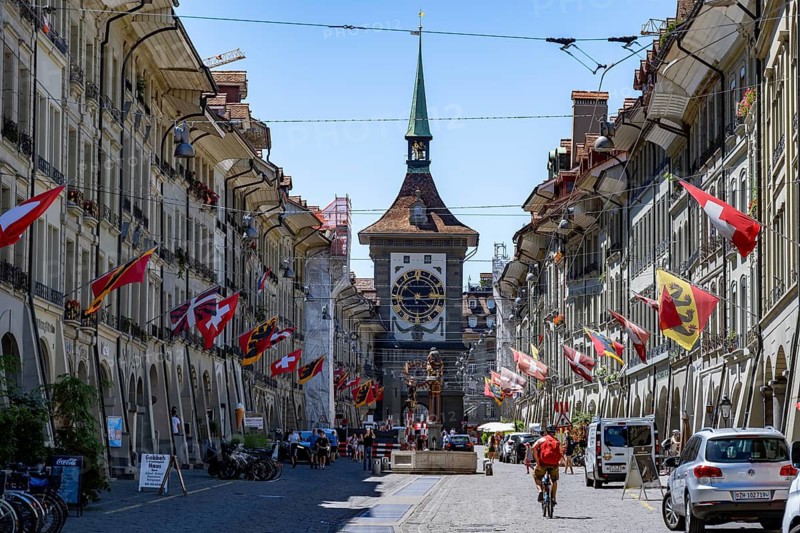 Kramgasse with historic houses decorated with cantonal flags and Swiss national flags, back clock tower Zytglogge, old town, Bern, Canton of Bern, Switzerland