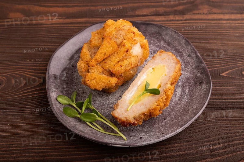 Chicken Schnitzel on gray plate with microgreen on brown wooden background. side view, close up