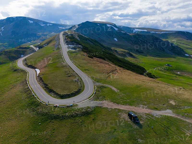 Curvy road leads through green mountains with a wide view of the surrounding countryside, aerial view, motorhome, camper, near Rânca, Ranca, Transalpina high road, Drum na?ional 67C, national road, Transylvania Alps, South Carpathians, Romania
