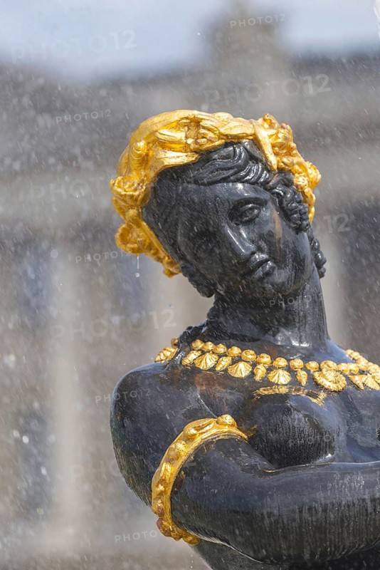 Detail of a bronze nymph from the Fontaine des Fleuves on the Place de la Concorde in Paris, decorated with golden ornaments and laurel wreath. The falling water envelops the figure and accentuates her mythological elegance and symbolic power, Paris, Île-de-France, France