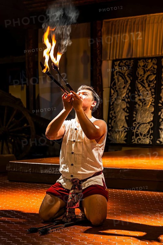 Young Thai man in traditional clothing in a historic show with burning torches, Old Chiang Mai Cultural Center, Chiang Mai, Thailand