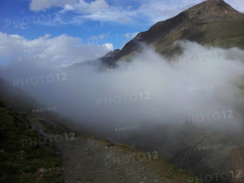 A hiking trail leads along a foggy mountain landscape, E5, hiking in the Alps, crossing the Alps, Austria
