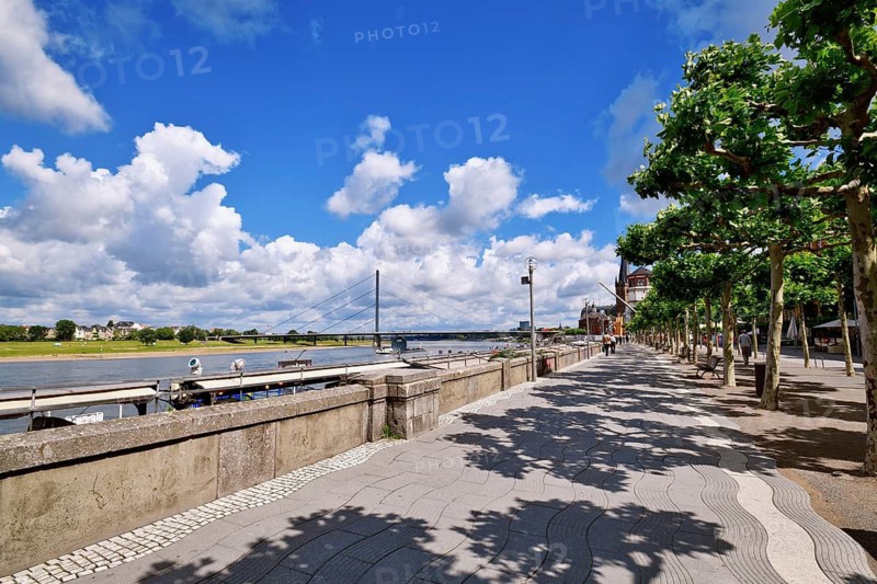 Düsseldorf, Germany - June 9th 2026: Riverside promenade 'Rheinuferpromenade' with Rhine River, and Oberkasseler Bridge on a sunny day