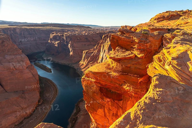Horseshoe bend, a dramatic meander of the colorado river, winds through the deeply eroded sandstone canyon, showcasing the unique geological formations and vibrant red rock colors under a clear sky