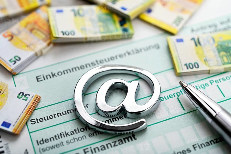 At sign on income tax return with bank notes, symbolic photo digital income tax return +++ editorial use only