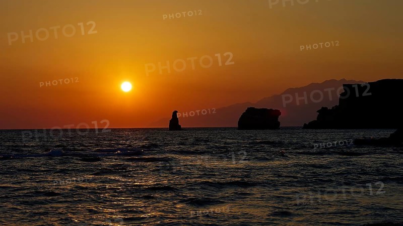 Calm sunset over the sea with mountains in the background and a rock in the water, sunset, south of the Amari Basin, Central Crete, Triopetra, rocks in the sea, Crete, Greek Islands, Greece