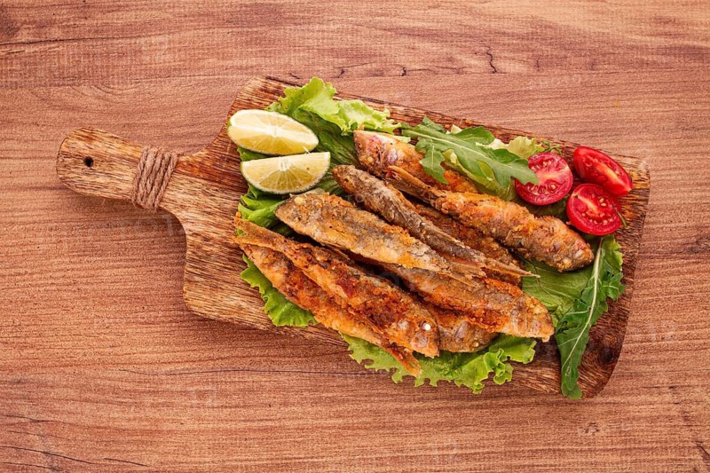 Fried crispy red mullet fish, on a wooden chopping board, with lime, no people