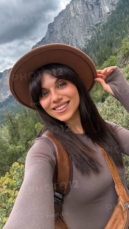 Smiling woman taking a selfie while enjoying the natural beauty of yosemite national park, embracing recreation and travel lifestyle outdoors with a scenic mountain backdrop