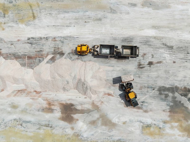 Excavator and lorry at a harvesting pan of the Walvis Bay Salt works. Aerial view. Drone shot. Walvis Bay, Namibia