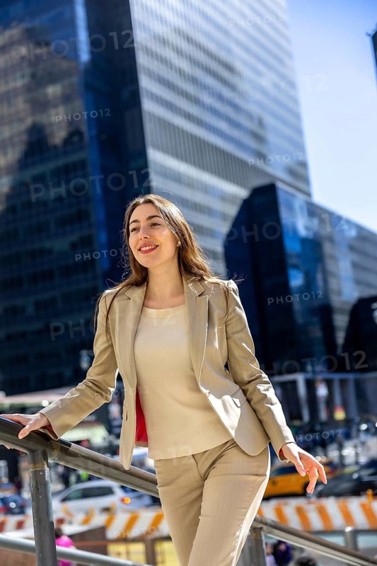 Young businesswoman standing outdoors in new york city, smiling and looking ahead with determination, reflecting future success and career growth in an urban corporate environment