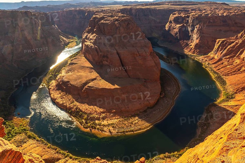 Horseshoe bend showcasing the powerful colorado river making a dramatic u turn around the sandstone canyon, highlighting the vast arid landscape and unique geological formation