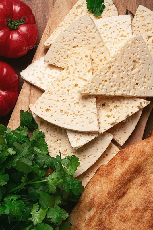 Georgian sliced cheese, on a wooden chopping board, with tomatoes with herbs and lavash, rustic style, Georgian cuisine, no people