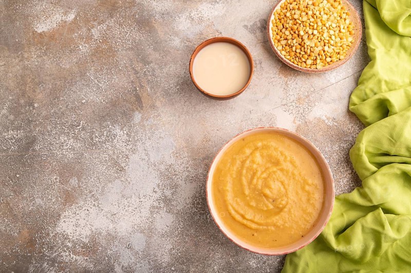 Pea cream soup, Puree, porridge in ceramic bowl on brown concrete background and green linen textile. Diet, healthy eating concept. top view, flat lay, copy space, minimalism