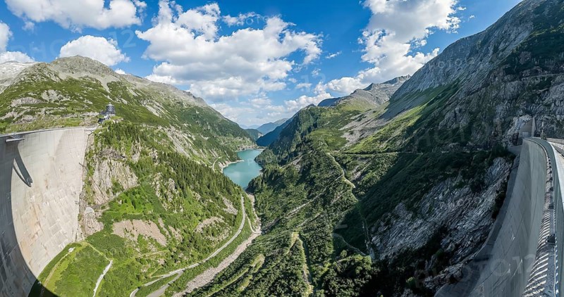 Panoramic view from air side facing away from water side of 200 meter high Kölnbrein dam with Airwalk viewing platform in the background, Galgenbichl Speicher reservoir reservoir in the middle back, Maltatal, Carinthia, Austria