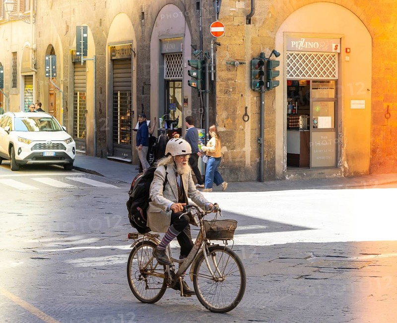 Senior man riding a bicycle in the alleys of the Tuscan city of Florence, Italy