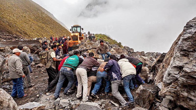 People work together to move a rock, with a tractor on a foggy mountain road, rockslide on the pass road towards Rurrenabaque through the Andes on the Road of Death in Bolivia