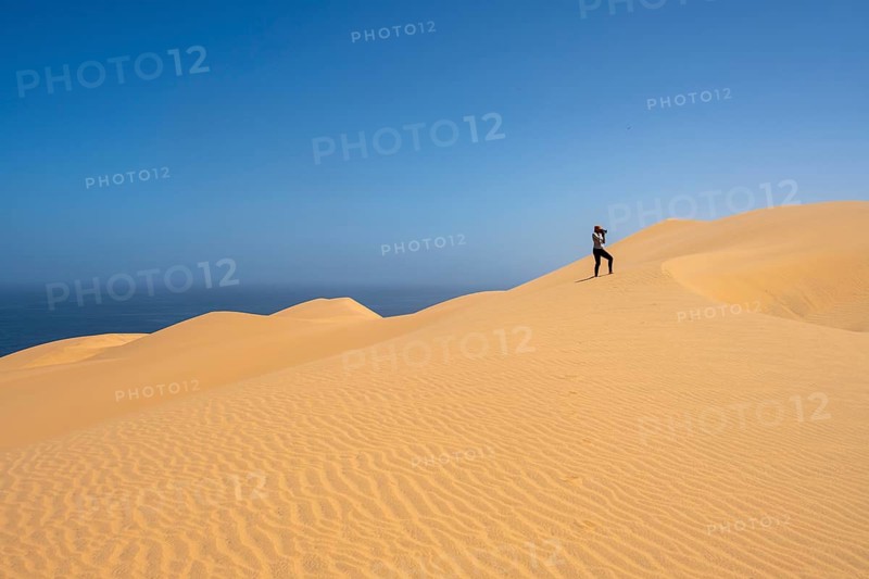 Photographer taking pictures with camera, standing on a dune, sand dunes with wave patterns, sea of dunes, sandy desert, impressive desert landscape, Namib Naukluft Park, Namib Desert, Namibia