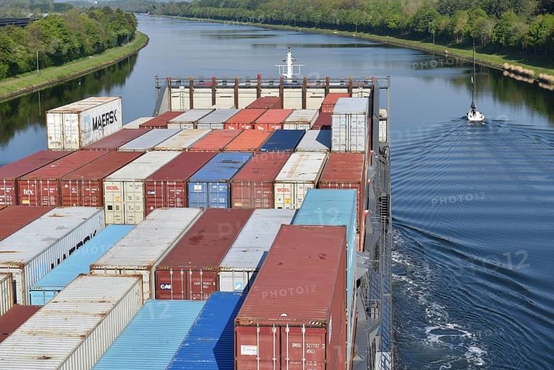 Ship with containers navigates calmly through waterway surrounded by trees, container ship sails through the Kiel Canal, NOK, Kiel Canal, Kiel Canal, Schleswig-Holstein, Germany