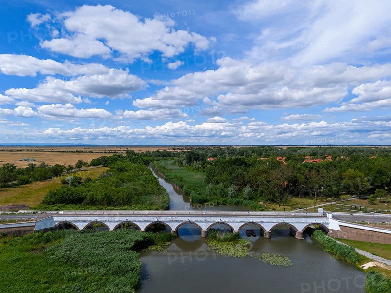 River landscape with a bridge and green vegetation, including a blue sky with white clouds, aerial view, nine-arched stone bridge, Kilenclyukú híd, Hortobagy, Hortobagy National Park, Hortobágyi Nemzeti Park, Hortobágyi Csillagoségbolt Park, Puszta, steppe area, UNESCO biosphere reserve, Hungary