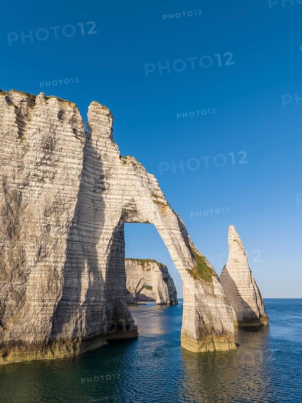Aerial view of the Porte d'Aval rock formation with the free-standing Aiguille d'Étretat rock pin in the morning sun, well-known sights and natural beauty on the chalk coast, behind it the La Manneporte rock gate, Étretat, Alabaster Coast, La Côte d'Albâtre, chalk cliffs, English Channel, Seine-Maritime, Normandy, France