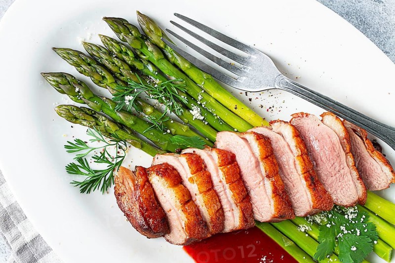 Roast duck breast, with asparagus, with red sauce, on a white plate, homemade, no people