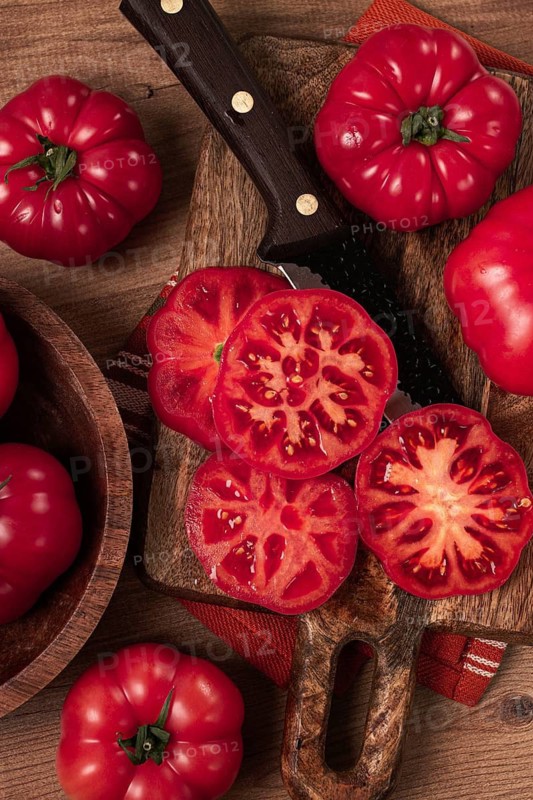 Freshly sliced, pink tomatoes, on a wooden chopping board, with a knife, rustic style, close-up, no people