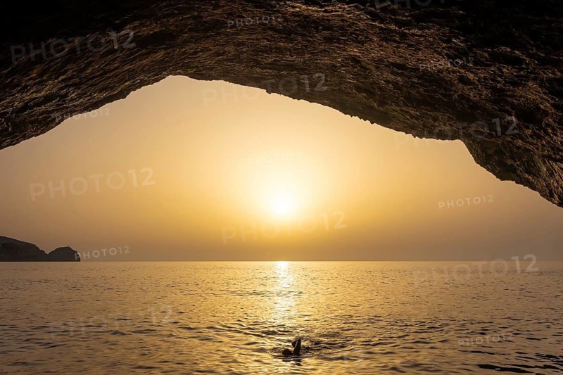 Seen from the Blue Grotto off Cabrera (Majorca), the sun sets on the horizon over the sea, Cabrera, Majorca, Spain
