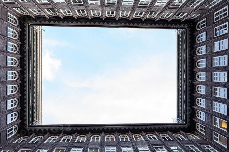 11.6.2018: Low angle perspective of the inner courtyard of the Chilehaus in the Kontorhaus district. The dark brick expressionist architecture features many windows and a sharp, triangular sky view. Hamburg, Germany