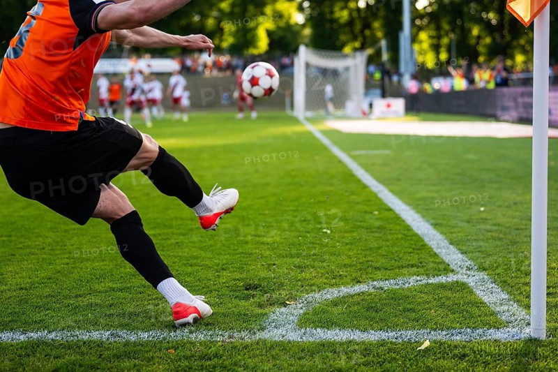 A soccer player kicking a ball from the corner line during a professional football match on a bright sunny day in Glogow, Poland