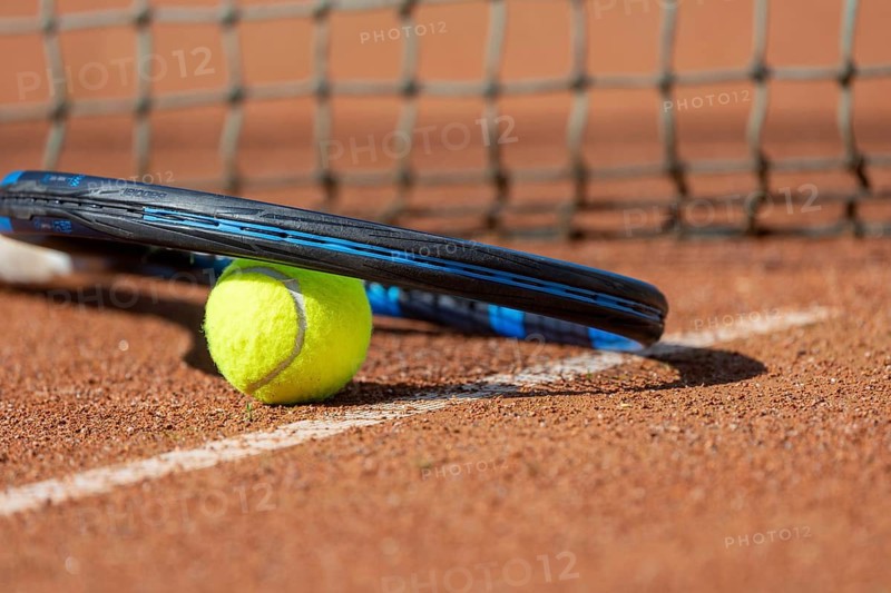 Tennis icon: close-up of a tennis ball and tennis racket on a clay court