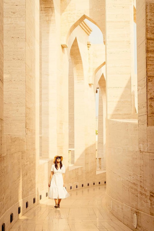 Doha Qatar Katara Cultural Village woman in white dress walking amphitheater traditional architecture arches stone columns heritage landmark tourism Middle East culture travel lifestyle