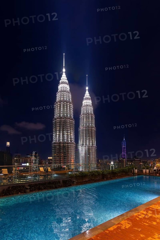 Swimming pool and Petronas Towers, KLCC Twin Towers, interlinked pair of 88-storey illuminated at night in capital city Kuala Lumpur, Malaysia