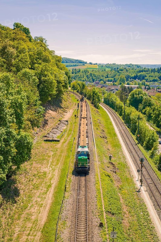 A train travels through a green, hilly landscape in clear summer weather, electrification of the Hochrheinbahn, conversion of the railway station, Waldshut, Tiengen, Germany