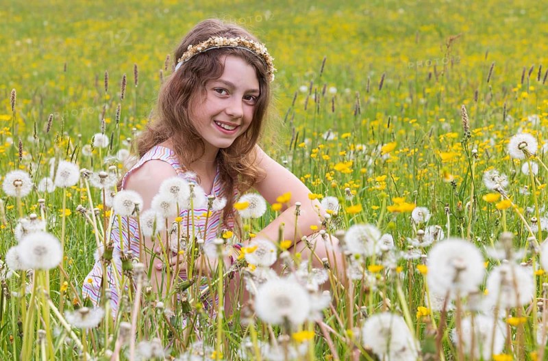 Portrait of a smiling girl sitting in a flower meadow, Mondsee, Salzkammergut, Austria