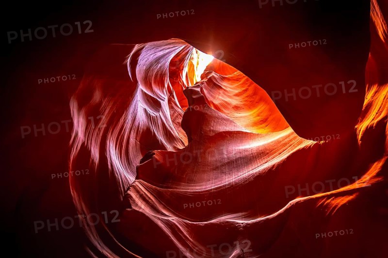 Antelope canyon showing narrow sandstone walls sculpted into distinctive flowing shapes by water erosion and wind, revealing vibrant orange and red colors with shafts of light from above