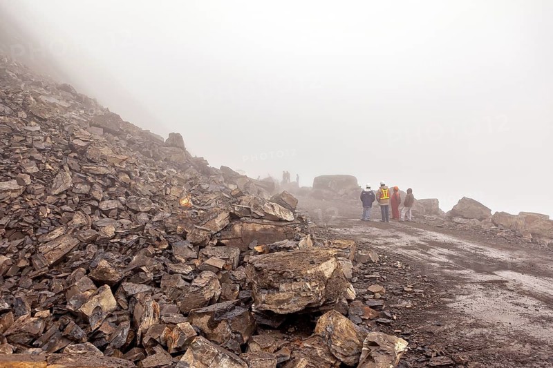 Construction workers stand on a rocky road in a foggy environment, rockslide on the pass road towards Rurrenabaque through the Andes on the Road of Death in Bolivia