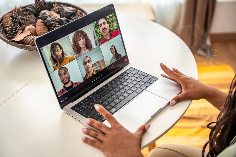 Woman's hands resting on a laptop during an online group therapy session, connecting diverse diverse people through video call for mental health support and counseling