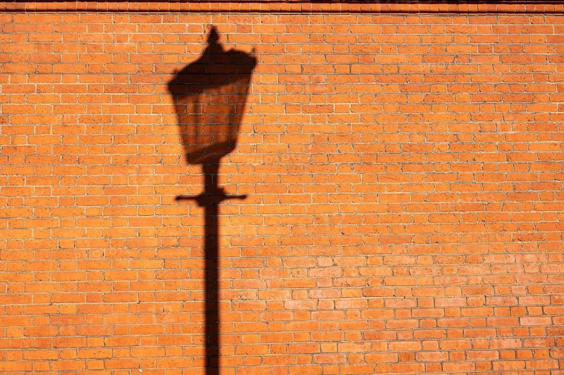 Shadows of a historic street lamp on reddish brown bricks in the evening light, Sloane Square, Borough of Chelsea and Kensington, London, England, Great Britain