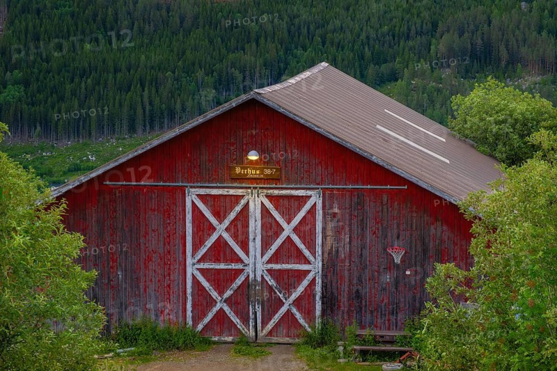 View of an illuminated entrance to an old barn in the mountains at dusk, Gol, Halligdal, Buskerud, Norway