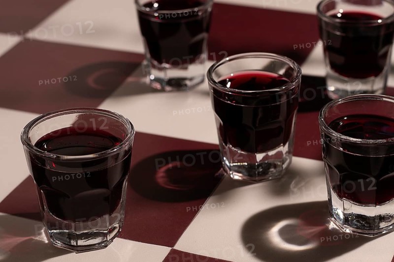 There are small glasses with a red drink on the table. chocolate liqueur, Soft light creates shadows on the surface