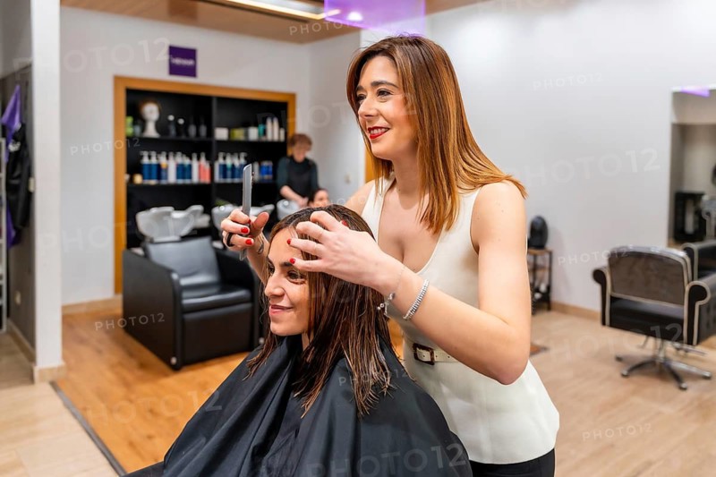 Professional female hairdresser styling a client's wet hair with a comb and hands, preparing for a fresh haircut at a modern hair salon, providing beauty and grooming services