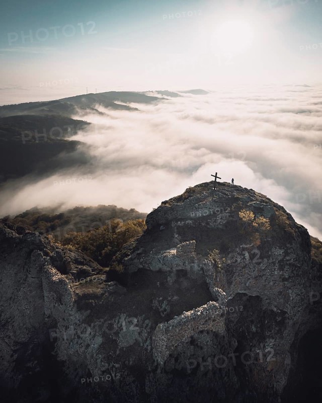 Dramatic Aerial view of Kojori fortressabove the clouds with person sillhouette and cross on top. Kojori.Georgia