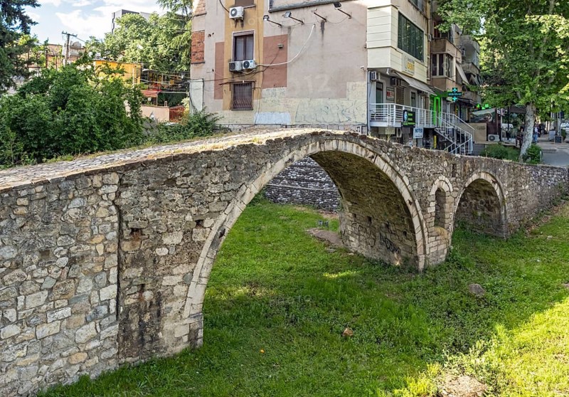 Tanners' Bridge - historic Ottoman-era stone footbridge - surrounded by green grass and city buildings, Tirana, Albania