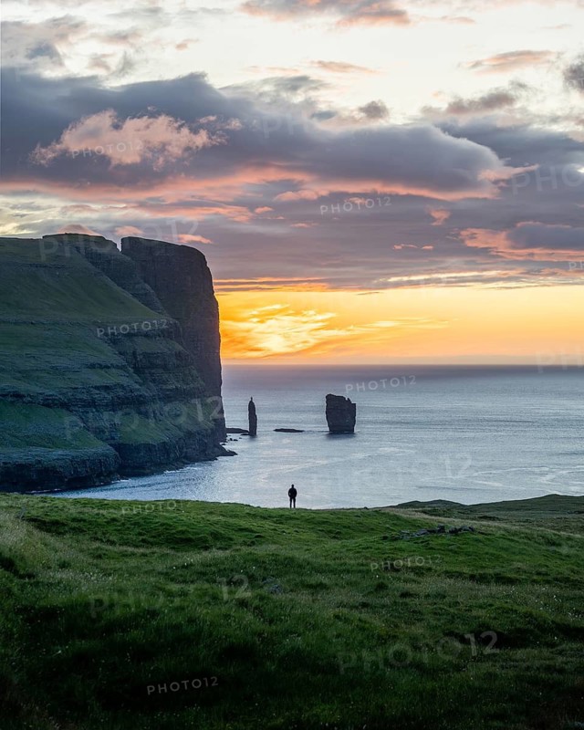 Person on a rock edge off the coast near Gjogv, Faroe Islands
