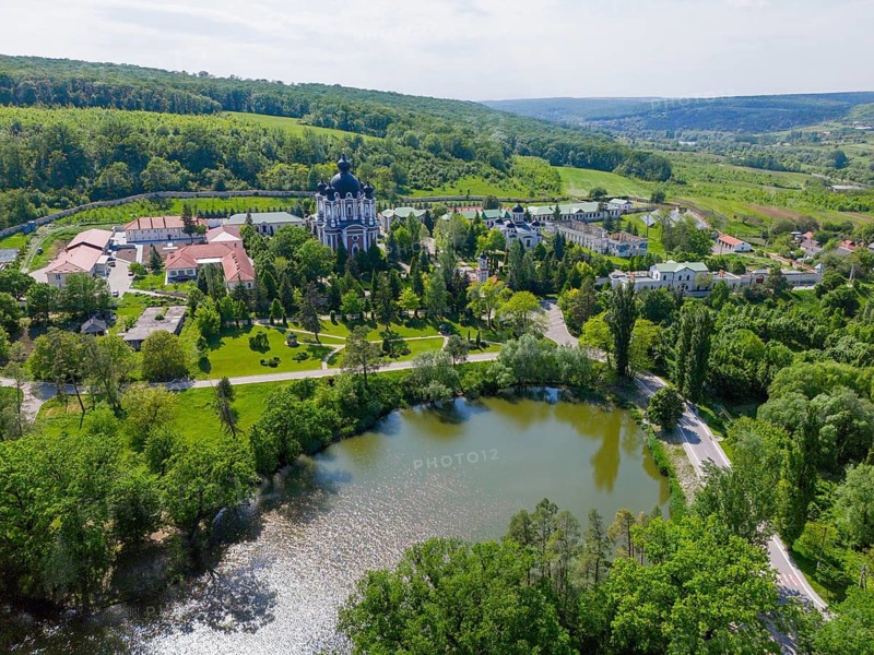 Landscape view with calm lake, hills and a cathedral on the horizon surrounded by green nature, aerial view, Cathedral of the Nativity of the Virgin Mary, Curchi monastery, Orhei district, Republic of Moldova, Moldova