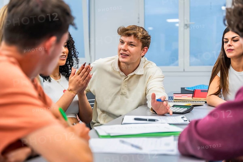 Young adults actively participating in a classroom setting, engaging in a lively group discussion while learning and working together during a university lecture