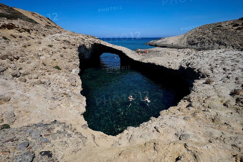 Two swimmers under a natural rock bridge in turquoise water, Kapras, Kapros, Beach, Kapros Beach, Caves, Paralia Kapros, Milos, Cyclades, Greek Islands, Greece