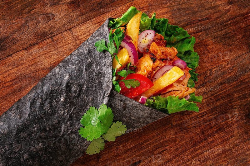 Shawarma in black lavash, on a wooden background, chicken shawarma, no people